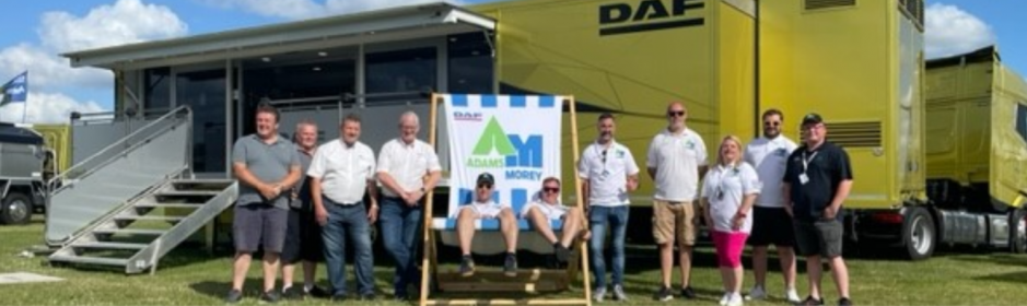 Group of people outside a large yellow truck and two people sat in deck chair