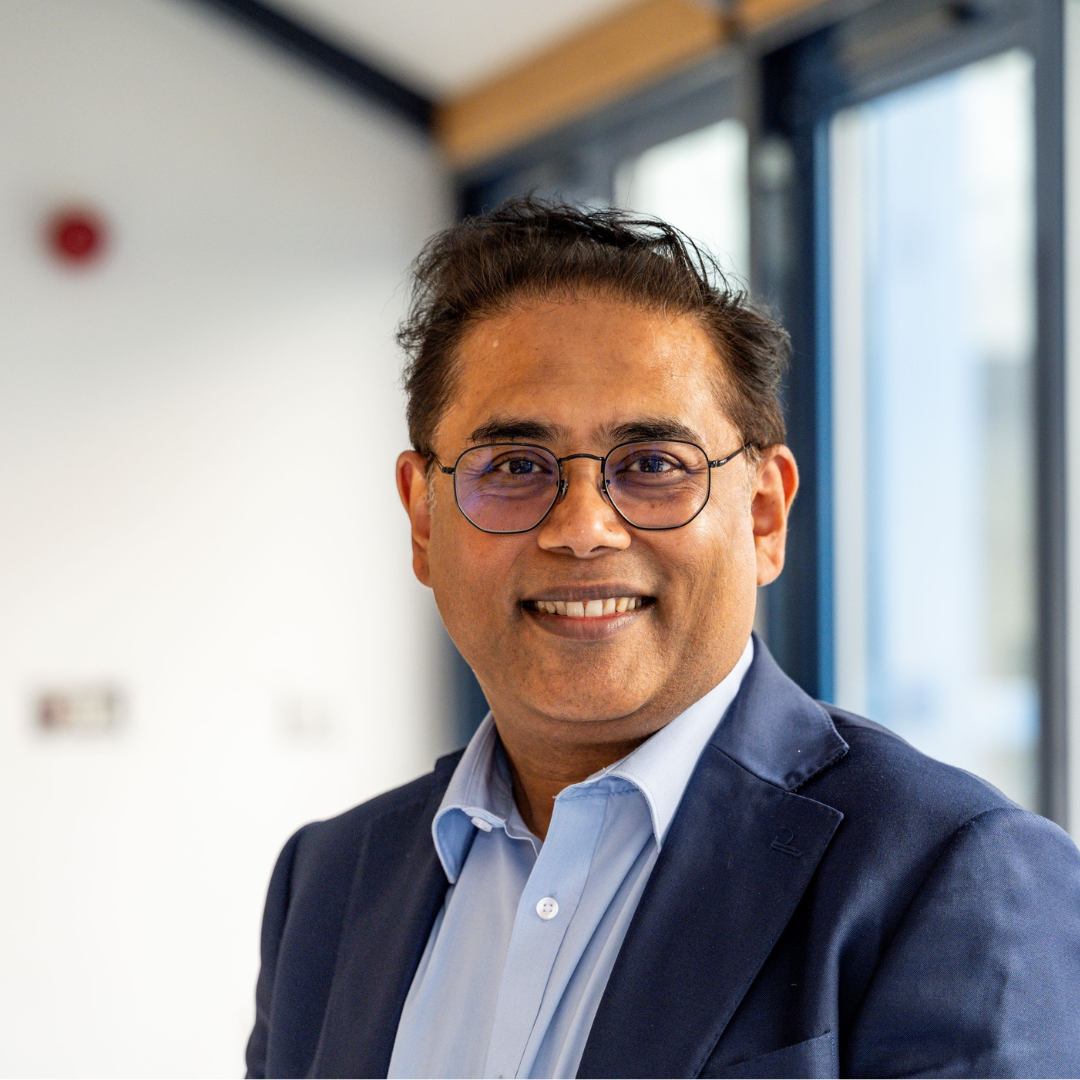 Parwez Hossain smiling at the camera in a blue suit with light blue shirt. 