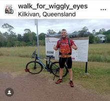 Walk for Wiggly Eyes Mikey standing in front of his bicycle