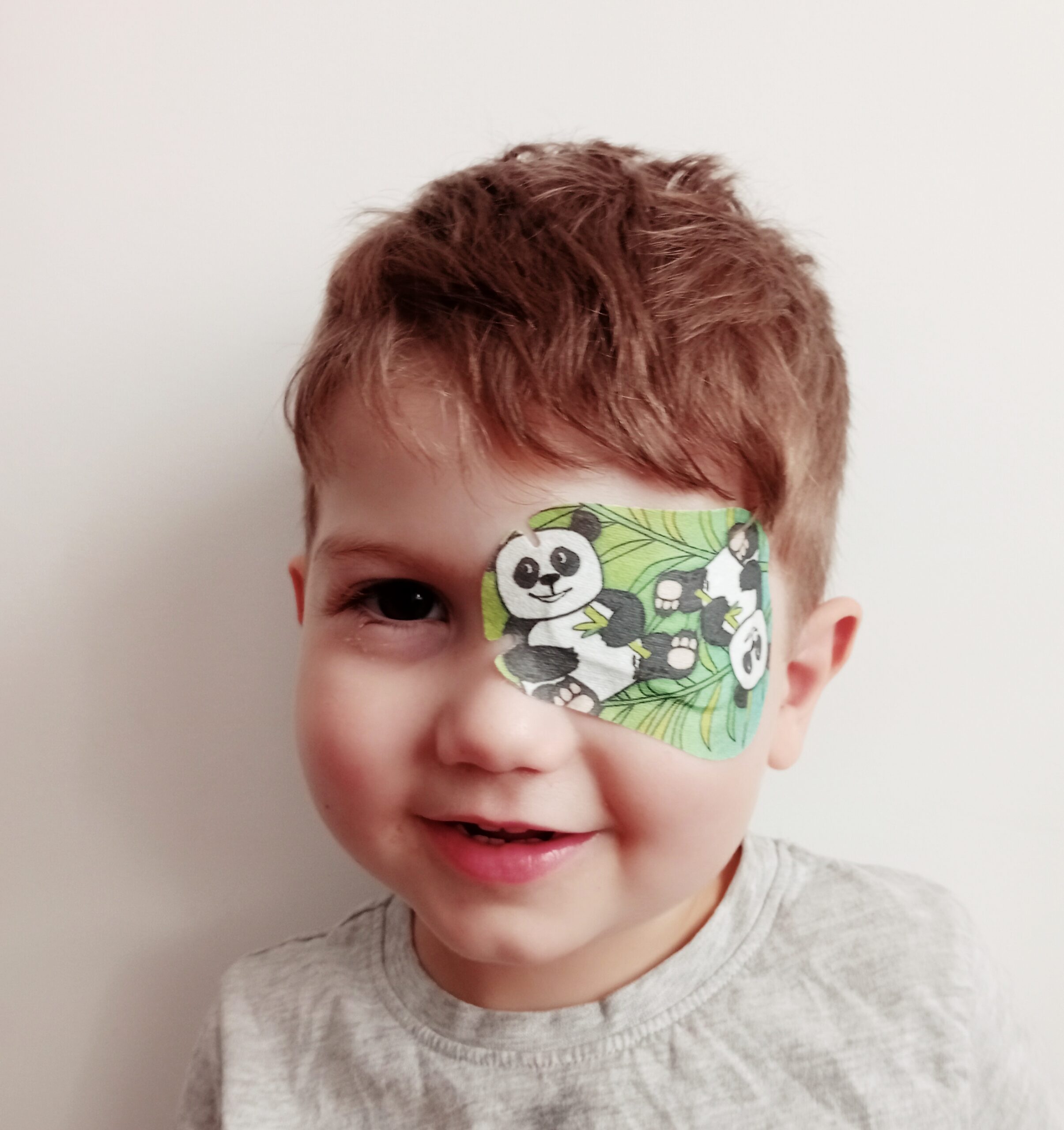 Patching study child wearing green eye patch with pandas on it