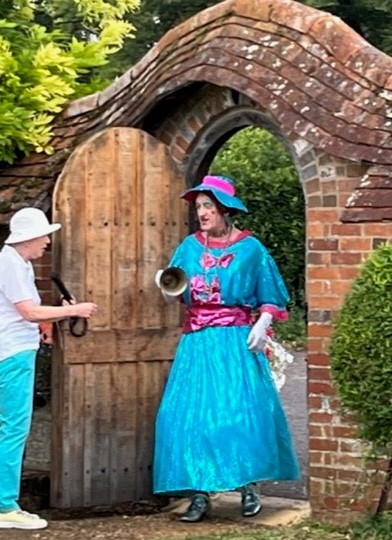 Granny Bean arrives Granny Bean - panto dame arrives in gate wearing blue and pink dress with hat